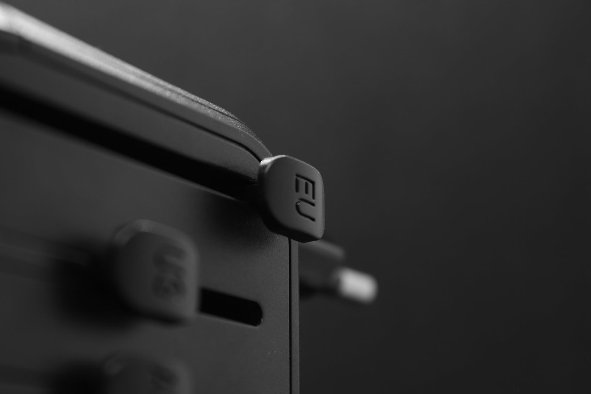 Zijaanzicht van de ELEKSO wereldstekker met focus op UK- en AUS-schuifuitgangen, klaar voor gebruik.

