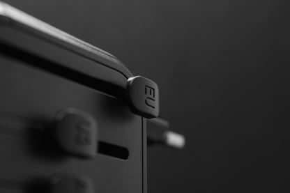 Zijaanzicht van de ELEKSO wereldstekker met focus op UK- en AUS-schuifuitgangen, klaar voor gebruik.

