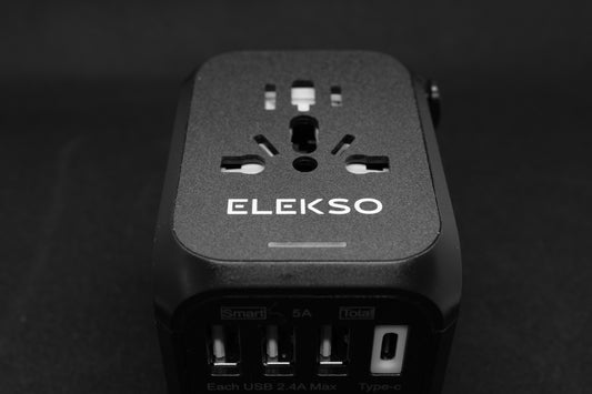 Bovenaanzicht van de ELEKSO universele reisstekker met meerdere internationale invoerpoorten en vier USB-uitgangen, inclusief USB-C.