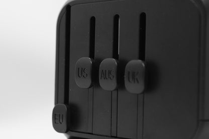 Zijaanzicht van de ELEKSO wereldstekker met afzonderlijke schuifknoppen voor VS-, UK- en Australische stekkers.