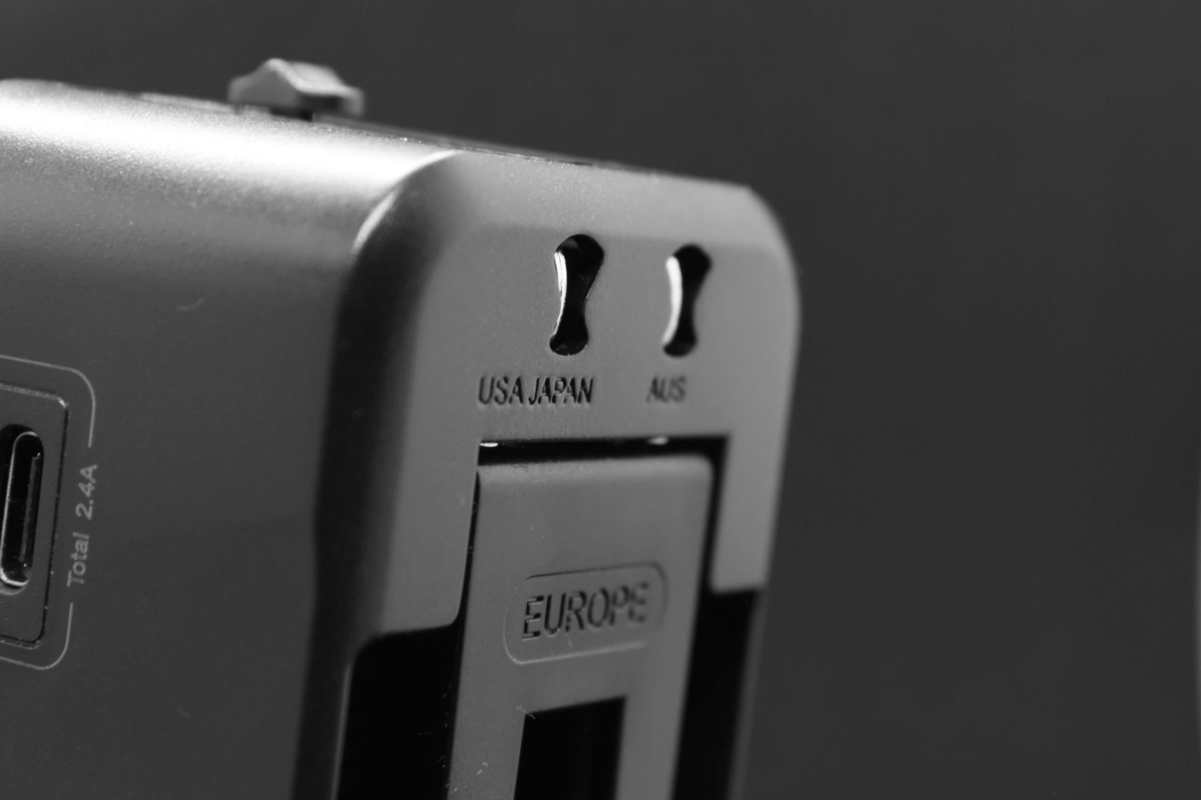 Detail van de zijkant van de ELEKSO reisstekker met schuifknoppen voor type A, C en G stekkers, geschikt voor VS, Europa en Australië.