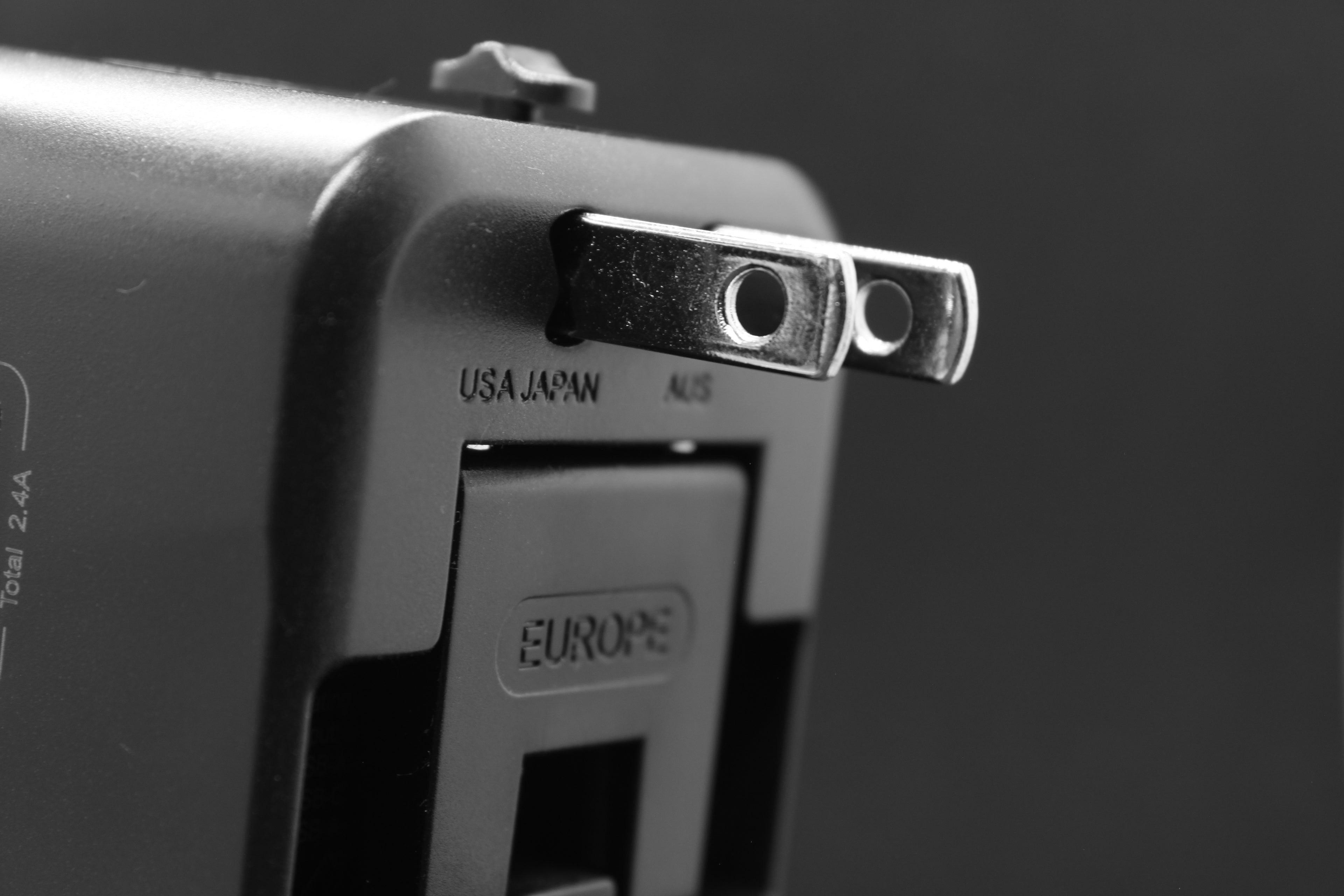 Zijaanzicht van de ELEKSO wereldstekker met USB-uitgangen en duidelijk gemarkeerde schuifmechanismen voor internationale stekkertypes.