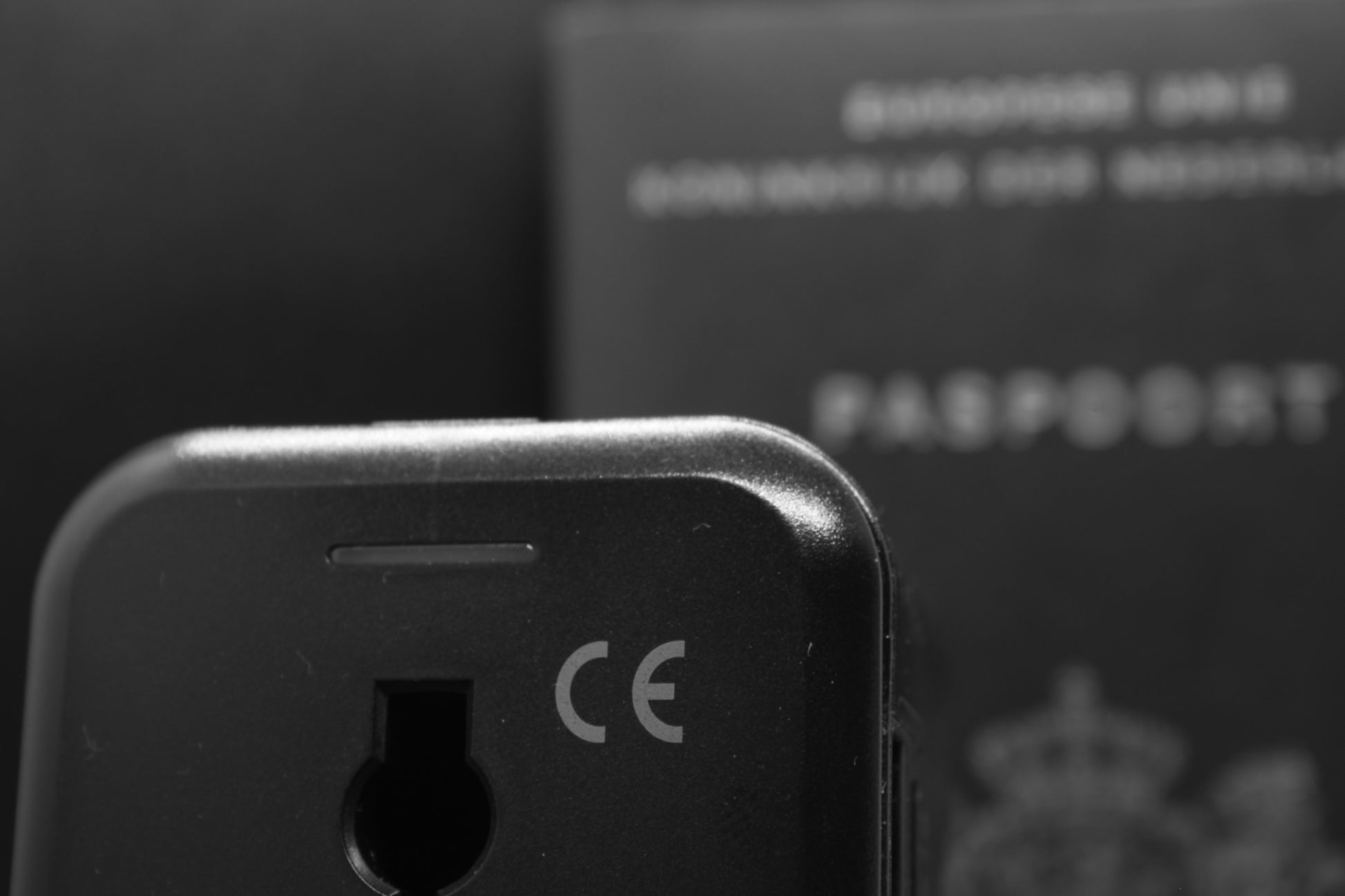 Achterzijde van de ELEKSO universele reisstekker met CE-markering, met een paspoort op de achtergrond — perfect voor internationale reizen.