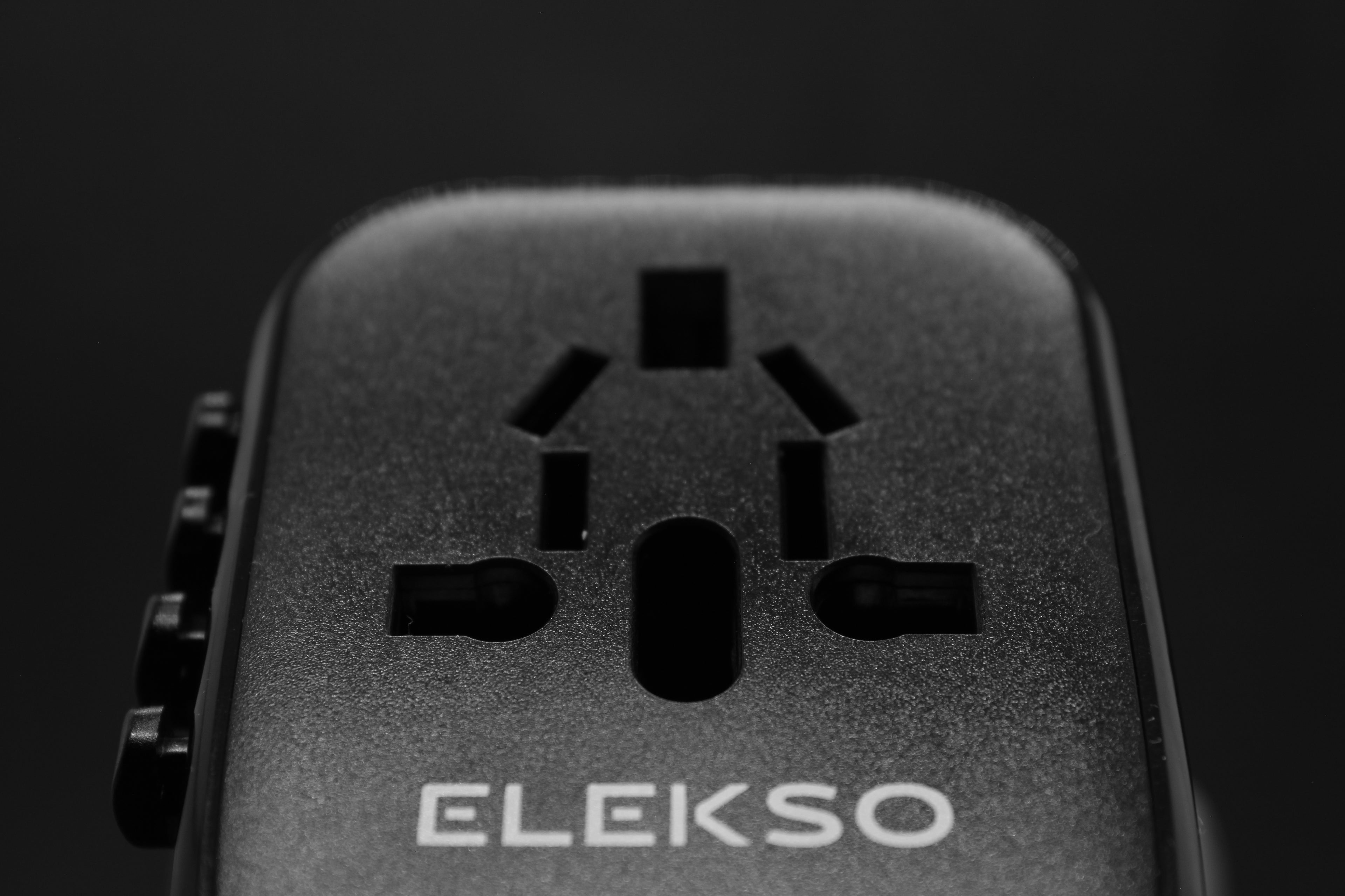 Close-up van het bovenste deel van de ELEKSO stekker met ingegraveerd logo en internationale invoerpoorten.